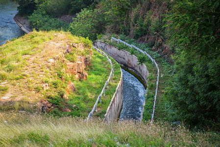 山坡上的排水坝库有运河和排水系统流向河自然森林背景图片