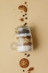 巧克力薯片饼干成分放在玻璃罐里彩纸背景平底图片