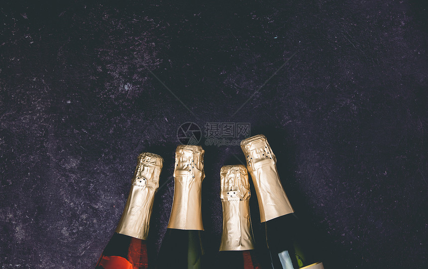 黑暗背景的四瓶香槟平的庆祝概念图片