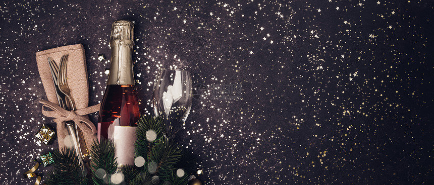 香槟酒瓶装着圣诞饰品在黑暗背景上平坦的党概念图片