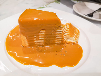 用奶茶酱和白色盘子上美味的自制蛋糕切片图片
