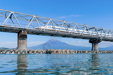 东海道Shinkansen列车快速驾驶和经过东京火车站附近的藤田山在日本静冈富士河上架着钢桥背景