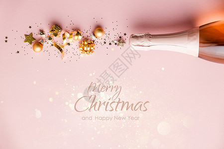 粉红色的静脉彩带星圣诞球和彩蛋的金装饰从香槟瓶子上飞来平躺着节日概念圣诞背景喜庆装饰和文字圣诞快乐和新年欢庆的平板香槟瓶子和金装饰粉红背景和背景