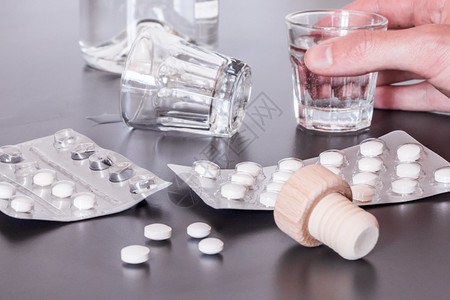 灰色桌上的药丸和酒精物滥用的概念图片