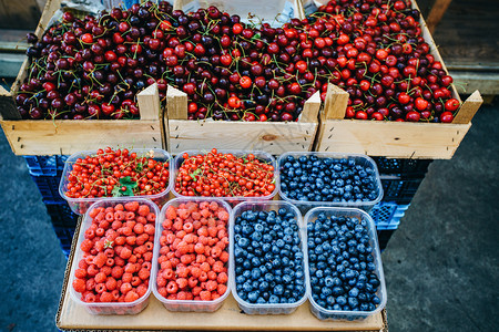 市场上的新鲜果子草莓蓝黑樱桃和红花草图片