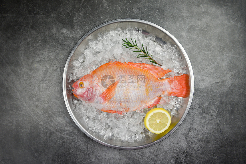 冰上新鲜的鱼含草药香料迷迭和柠檬原生鱼黑底的红罗非图片