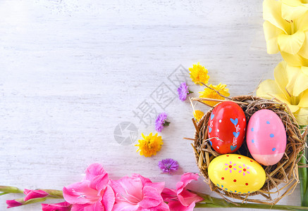 复活节鸡蛋装在篮巢饰中花朵多彩在白底面最高视图图片