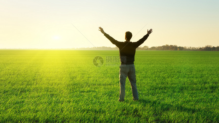 绿色草原上的人举起手来情感场景图片