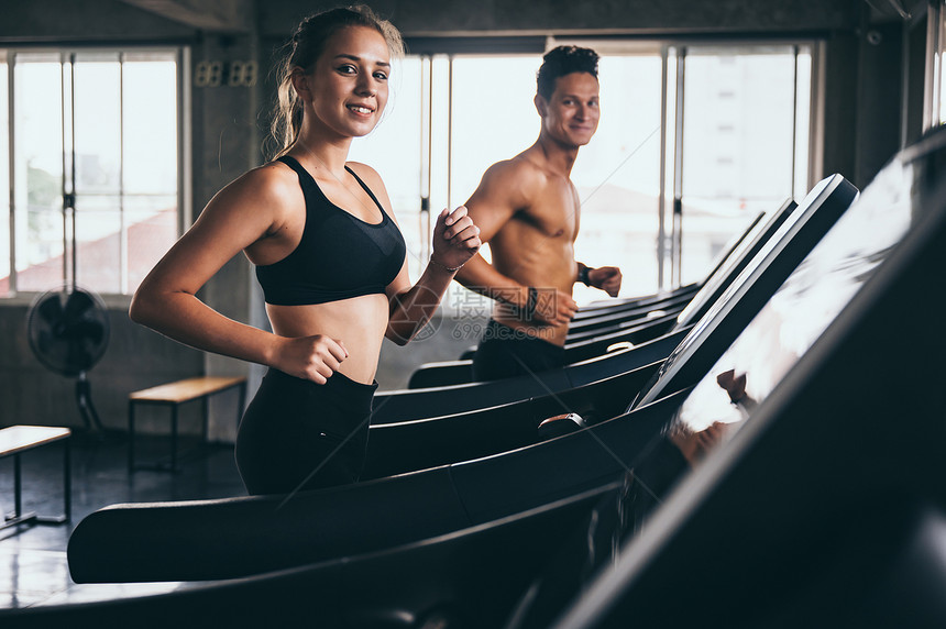 年轻夫妻在健身房跑步机上一起运动图片