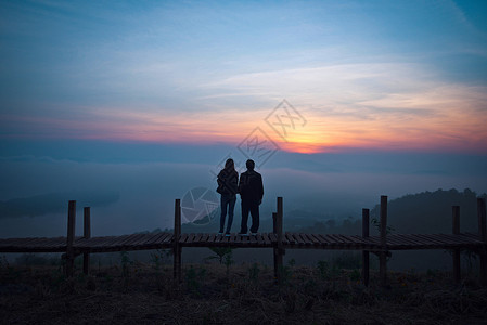 情侣站在木桥上欣赏日出图片