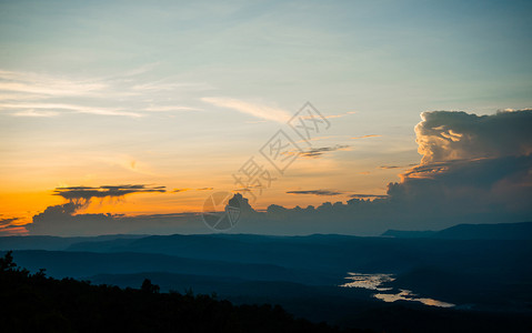 美丽的日落云和橙黄色天空在山上的黄昏夜晚风景中有河流背的背景图片