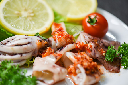 沙拉加辣椒酱药草和香料海产食品店盘子上的鱿鱼片背景图片