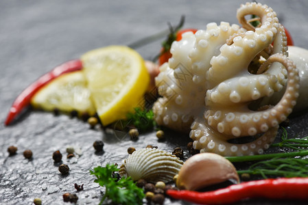 海食鱿鱼板海洋美食晚餐黑底带草药和香料的章鱼新鲜触角图片