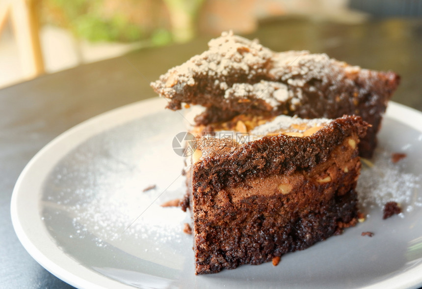 桌子一块巧克力蛋糕可上面有坚果的巧克力蛋糕可上面有坚果白板上巧克力蛋糕切片木桌背景图片