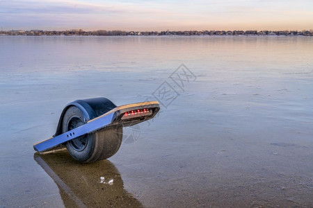 在科罗拉多北部冰冻湖上一个冷的单轮自行平衡电滑板个人运输机概念图片