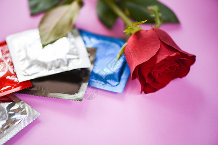 安全爱概念带避孕套和玫瑰的节育控制在粉红背景怀孕或传染疾病的鲜花爱图片