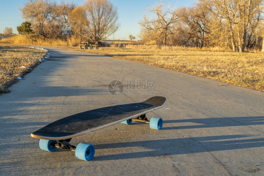 在科罗拉多州北博伊德湖公园的冬季风景中在一辆铺面的自行车道上驶驾长板乘坐蓝色轮子图片