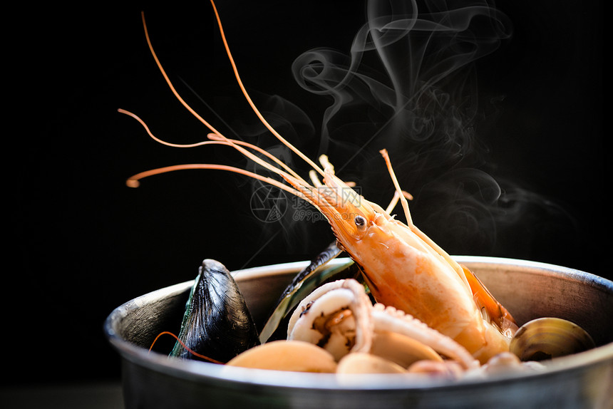 贝壳鱼海产板和虾鲜鱿鱼海洋美食晚餐烹煮的海产食品在热锅中煮熟底有草药和香料图片