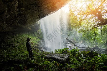 山河流洞穴前的景观瀑布和Trekking人一起在绿林自然树中图片