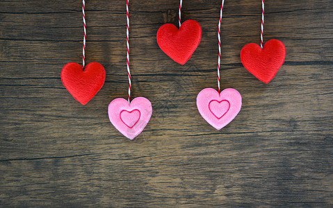 情人节爱心概念挂红色和粉心脏装饰在木制的纹身背景上图片