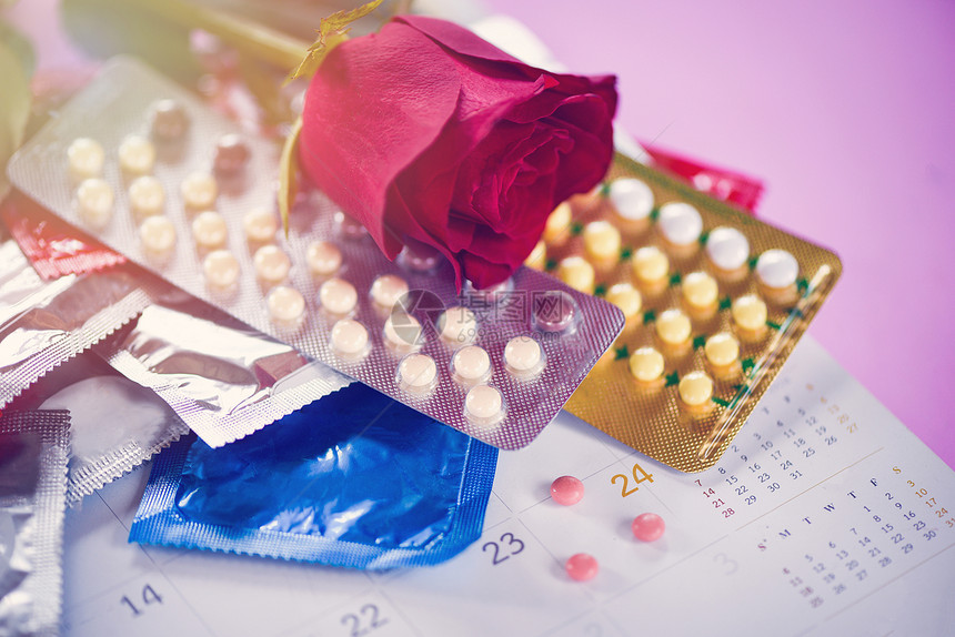 安全行为概念带避孕套的控制以及日历上的背景怀孕或传染疾病带避孕套的玫瑰和生育控制图片