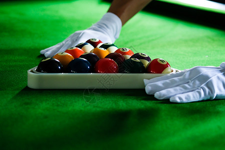 Man手和Cue臂在玩Snooker游戏或准备在绿色球桌上绿色盘上有多彩的Snooker球背景图片