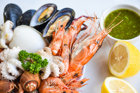 贻贝贝壳盘底白上的比伦贝壳螃蟹和海鲜酱柠檬烹饪蒸汽食品为海鲜自助餐服务的概念背景