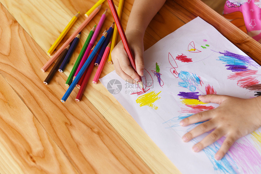 女孩在纸上画在家中木制桌上用彩色铅笔画孩子画和彩色蜡笔图片