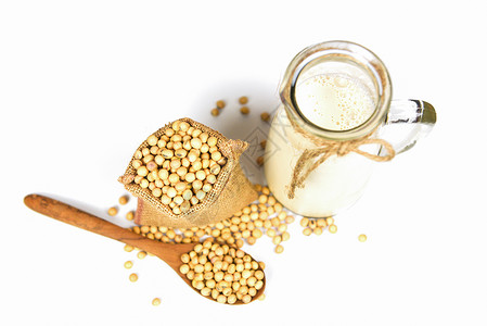 用于健康饮食和自然豆蛋白质的玻璃罐中豆奶用于健康的饮食和天然豆蛋白木勺中的豆和白底孤立的袋中干豆背景图片