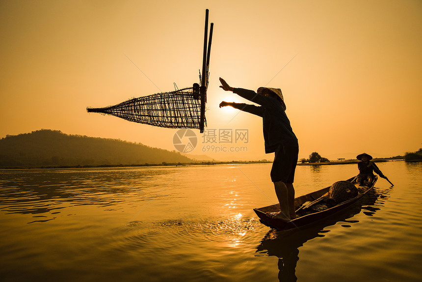 渔民在船上河日落亚洲渔民在木船日落或湄公河出木船落上捕竹鱼陷阱具有山地背景生命的Silhouette渔民船图片
