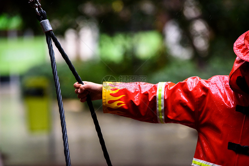 一名儿童消防员的手握着他臂在雨季伸到一根绳子上图片
