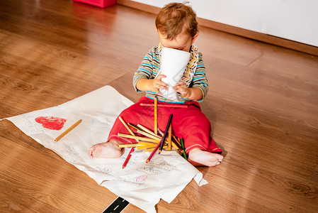 1岁的婴儿在地板上玩彩色铅笔绘画游戏图片