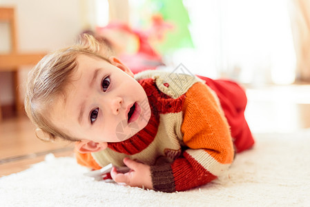 有趣的是美丽女婴对父母微笑她在家里的地板上滚图片