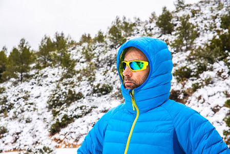 身穿蓝大衣和墨镜的登山者在闲暇时间雪山路上行走图片