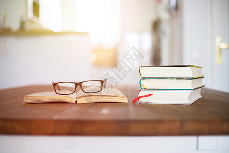 书本和眼镜堆在家中木制办公桌的书架上图片
