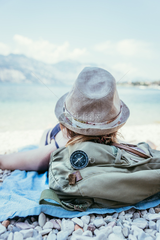 世界旅行前方的指南针女孩躺在海滩上背景模糊图片