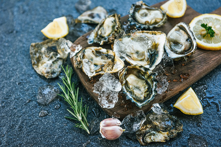 木板上新鲜的牡蛎海板底背景露天牡蛎贝壳配有草药香料柠檬迷糖餐桌和在厅美食中吃的冰上健康海鲜生牡蛎晚饭背景图片