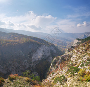 秋天清晨的山景与太阳束和烟雾进入峡谷图片