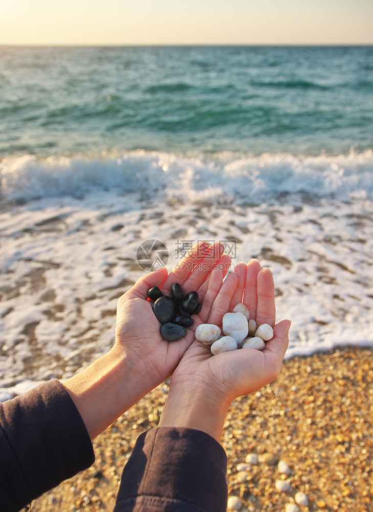 白色和黑的石头在海边女人手上自然的概念场景图片