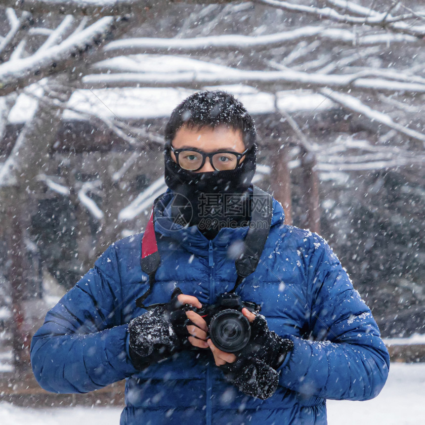 一张亚洲摄影师拿着照相机的肖像看着冬季白雪摄影机日本在旅行度假或节日期间的冒险概念自然背景图片