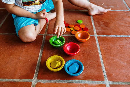孩童玩着一套彩色碗填满适当的颜色同时通过操控教育材料来学习计算图片