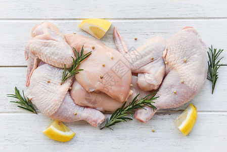 乳翼和双腿未烤鸡肉配有烹饪成分的鸡肉配有迷香柠檬药草和料的新鲜生鸡背景图片