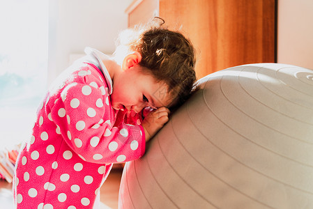 胆小的孩子害羞的婴儿躲在外表之穿着粉红色睡衣在卧室里背景