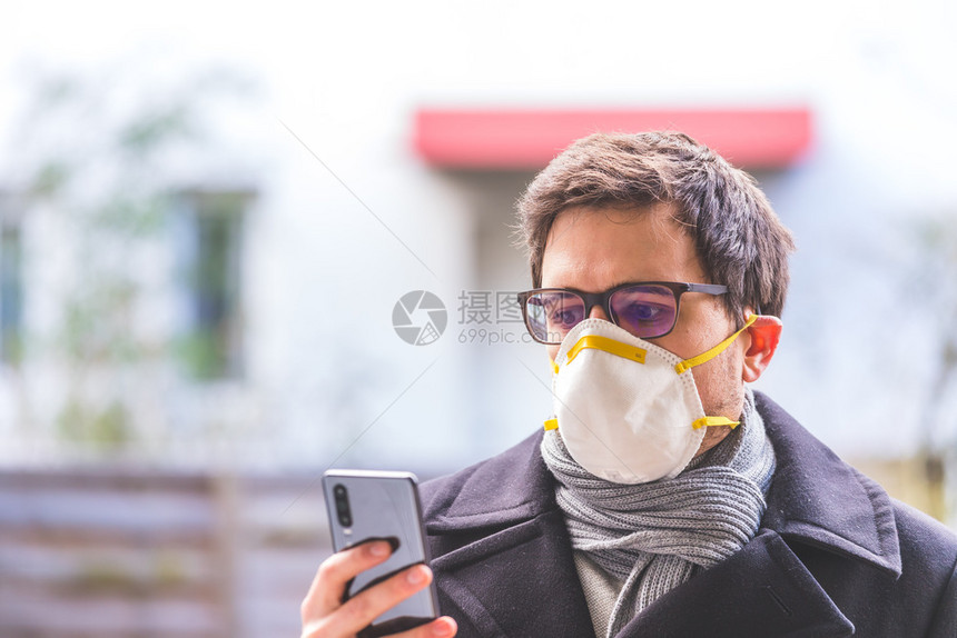 年轻商人户外有呼吸口罩和智能手机风科罗纳季节图片