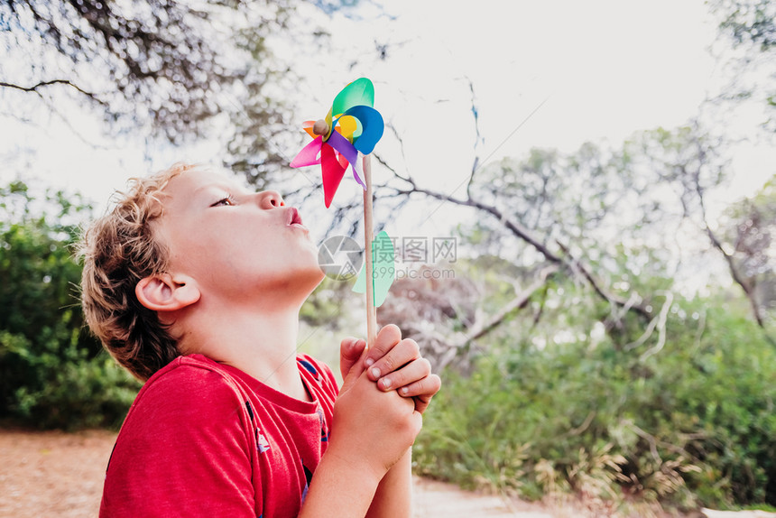 金发男孩在森林里玩耍带着多彩的风车吹带着笑脸图片