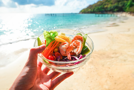 沙拉虾水果和新鲜生菜番茄胡萝卜椒沙滩上健康食物高清图片