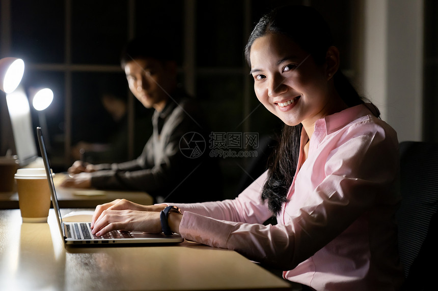 年轻成的亚洲商人和妇女深夜在办公室用台式计算机和笔记本电脑工作图片