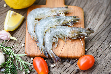 木制切板上新鲜虾配有食用海产品生虾的饲料草药和香背景图片