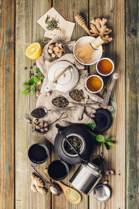 各种茶叶和壶成分干草药绿色黑茶和木制桌底的红茶平铺图片