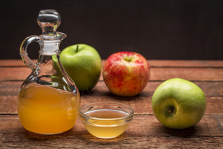 未经发酵的与母亲一起生苹果醋一块有小玻璃碗的结壳四周都是生锈木上的新鲜苹果背景